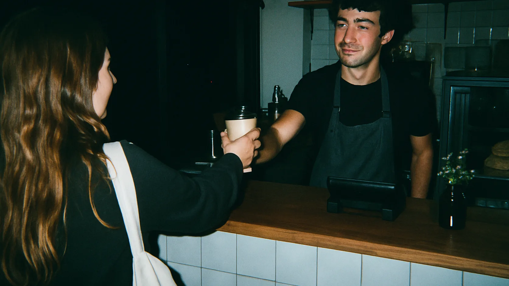 Mitarbeiter reicht einen Coffee-to-go über den Tresen einer kleinen Filiale